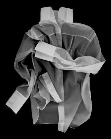 Wrinkled sheer white collared shirt with long sleeves on a black background, showcasing a modern and minimalist fashion item.