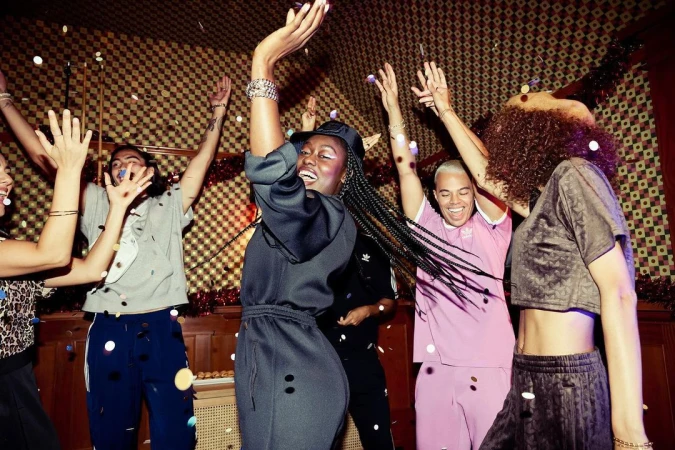 Enthusiastic group of diverse young adults celebrating under falling confetti, capturing a joyful and lively indoor party scene with warm lighting.