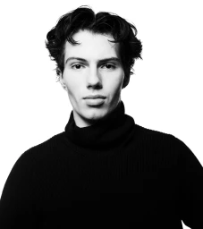 Monochrome portrait of a young man wearing a black turtleneck sweater against a plain white background.