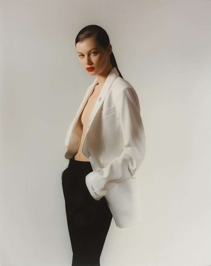 Model wearing an open white blazer and dark trousers against a neutral background by Julia Sariy