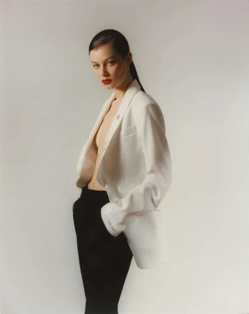 Model wearing an open white blazer and dark trousers against a neutral background by Julia Sariy