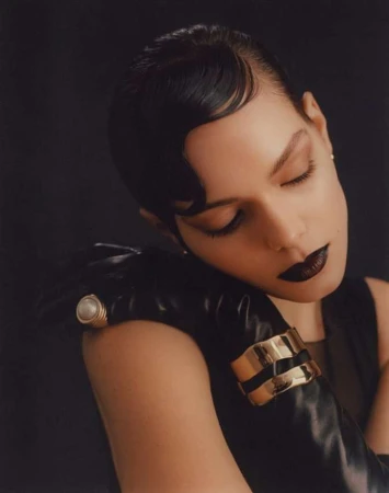 Close-up portrait of a woman with dark finger waves, dark lipstick, black leather gloves, pearl ring, and gold cuffs by Julia Sariy.