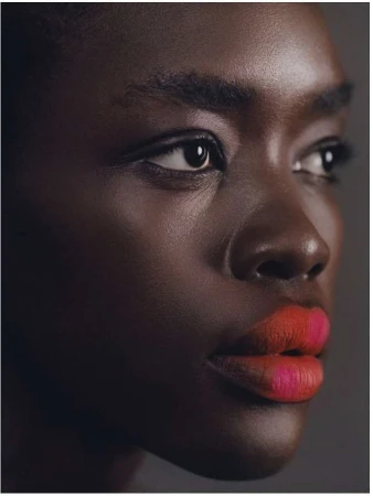 Close-up portrait of a Black woman with bold orange and pink lipstick photographed by Julia Sariy