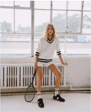 Blonde woman in a white tennis sweater and shorts holding a racket by Julia Sariy
