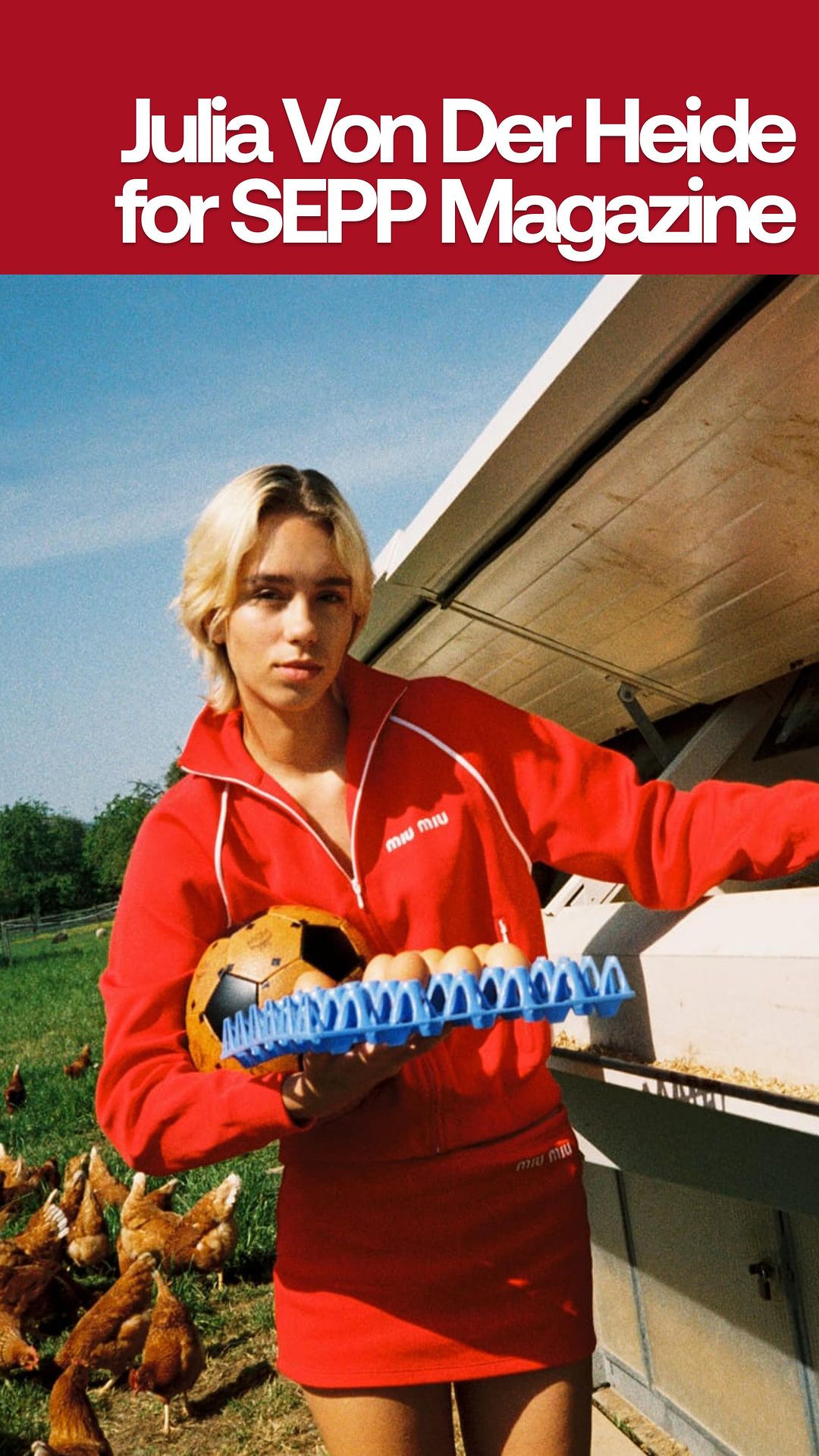 Blonde woman in a red tracksuit outside holding a carton of eggs and a soccer ball with chickens in the background on a farm.