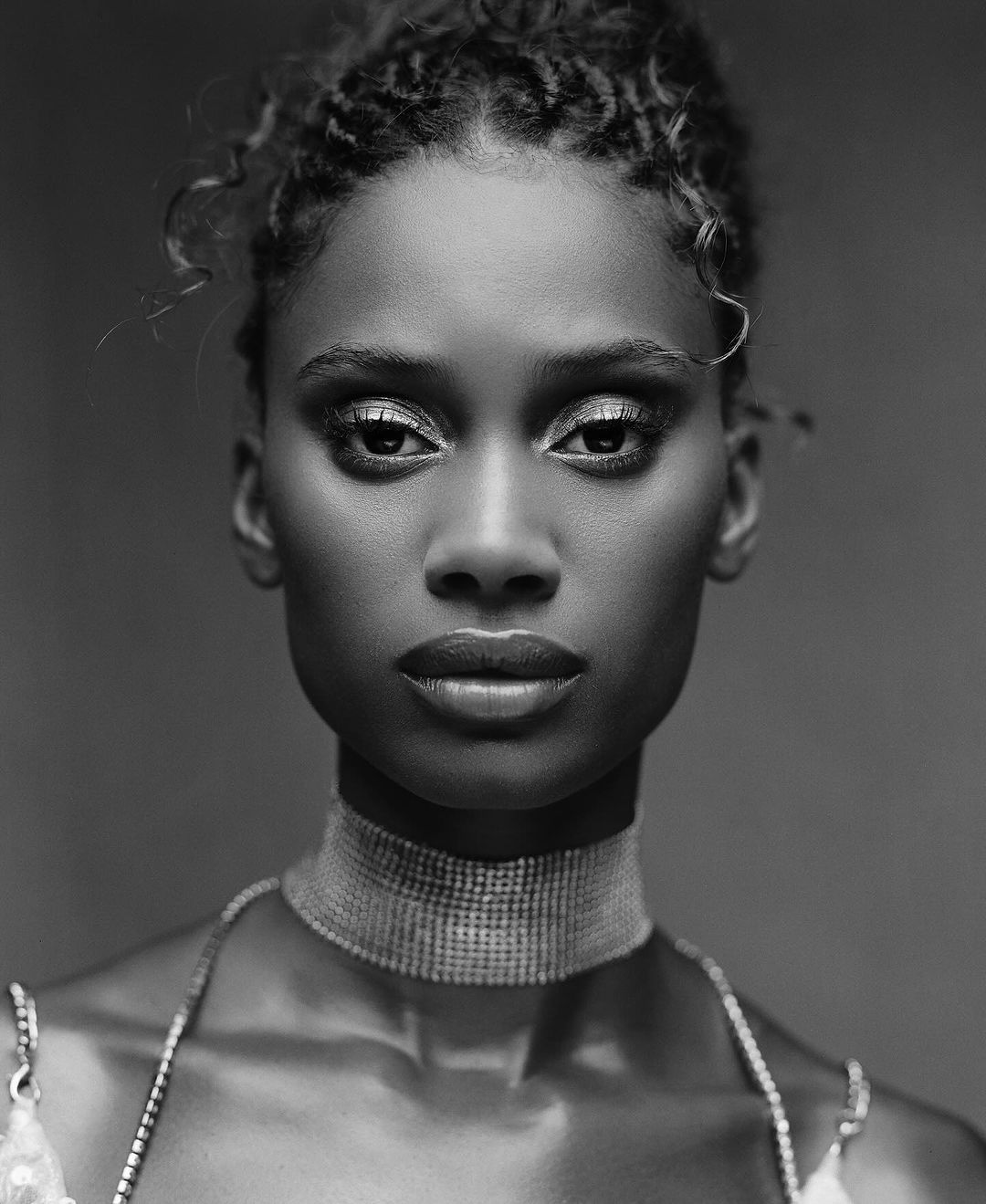 Close-up portrait of a woman in black and white with a high collar and bare shoulders, showcasing beauty and elegant fashion.