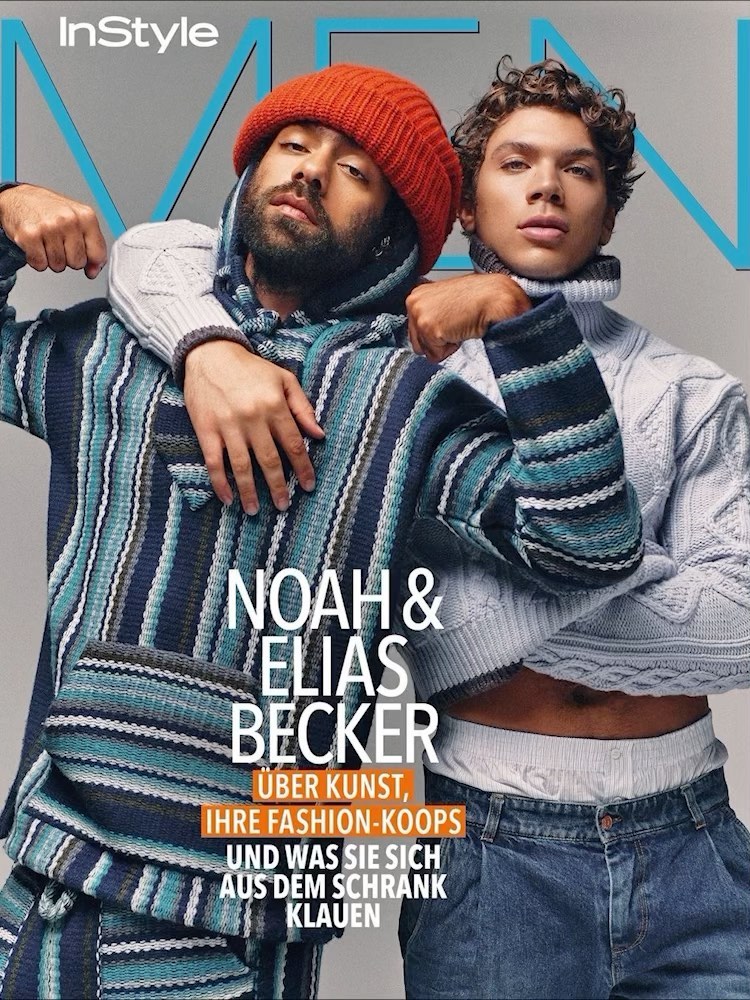 Magazine cover features two men in stylish knitwear. One wears an orange beanie and a striped hoodie. The other sports a gray turtleneck.