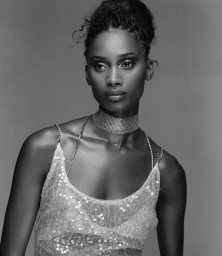 Black-and-white portrait of a woman wearing a sequined top and rhinestone choker necklace against a grey backdrop