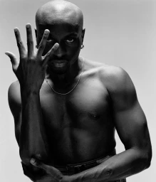 Portrait of a bald Black man holding his hand up with splayed fingers in front of his face, photographed by Julian Essink.
