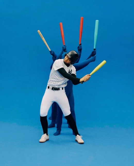 A baseball player in uniform swings a yellow bat, with blue-suited figures behind holding bats, all against a solid blue background.