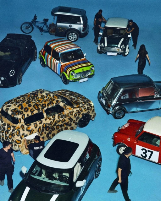 Overhead shot of several customized Mini Cooper cars in an array of colors, textures, and patterns, displayed on a bright blue studio backdrop.