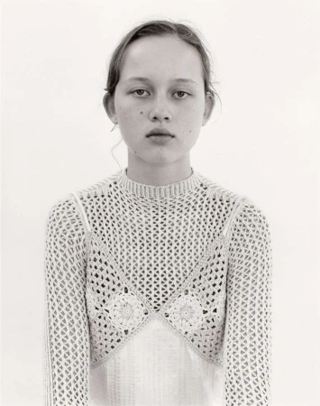 Portrait of a young woman wearing a textured crochet top against a plain white background