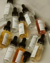 Overhead flat lay of glass dropper bottles with white labels arranged on a marble surface.
