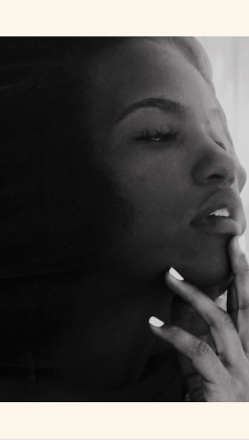 Monochrome portrait of a woman with her hand near her face. The woman is looking to the side in a soft and elegant studio setting.