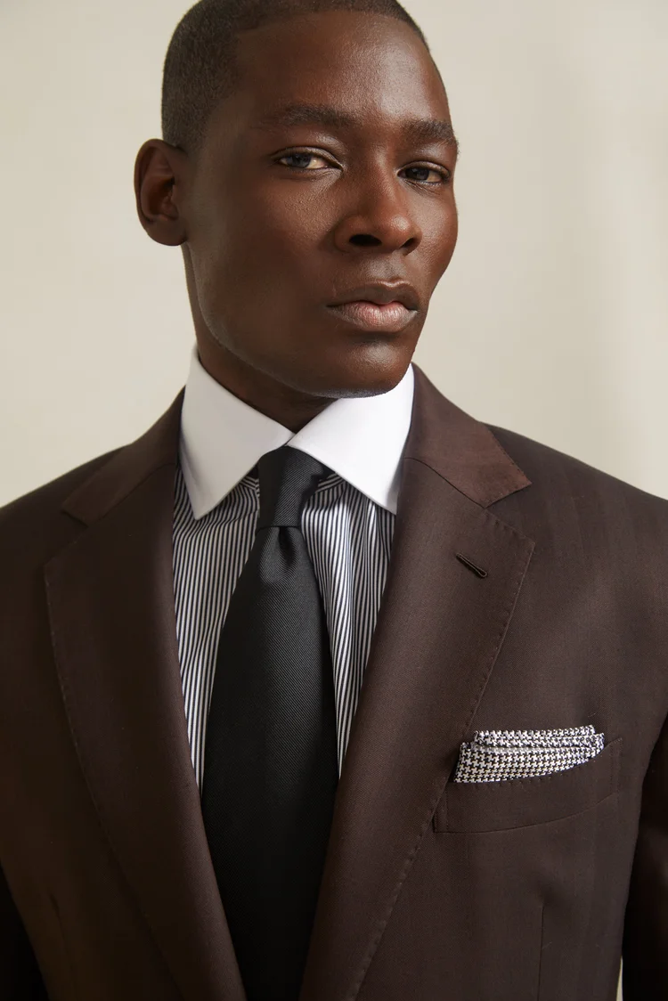 Portrait of a Black man wearing a brown suit, striped shirt, white collar, black tie, and pocket square by Elle Edwards