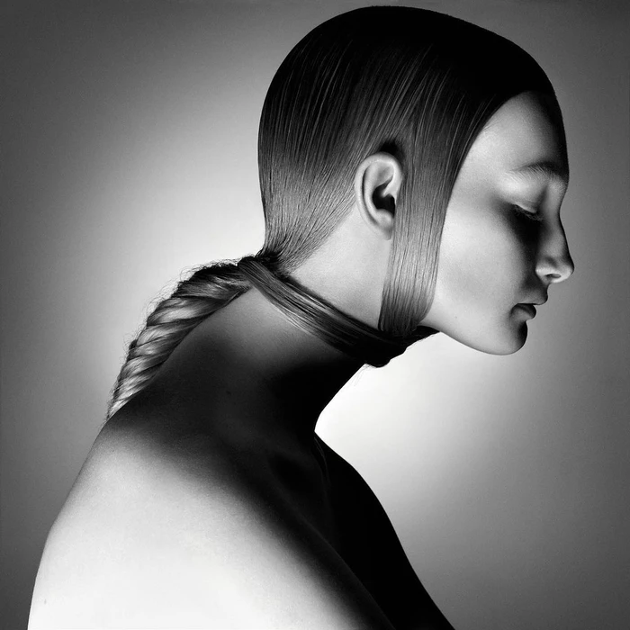Monochrome profile portrait of a model with sculpted sleek hair pulled tightly into a wrapped braid choker by Julien Martinez Leclerc
