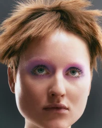 Close-up portrait of a woman with short spiky brown hair and vibrant purple eyeshadow shot by Juliette Allix.