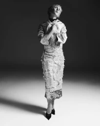 Model in textured metallic dress and black shoes posing against a gradient studio backdrop