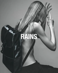 Model wearing a glossy black backpack against a grey studio background, photographed by Kai Cem Narin.