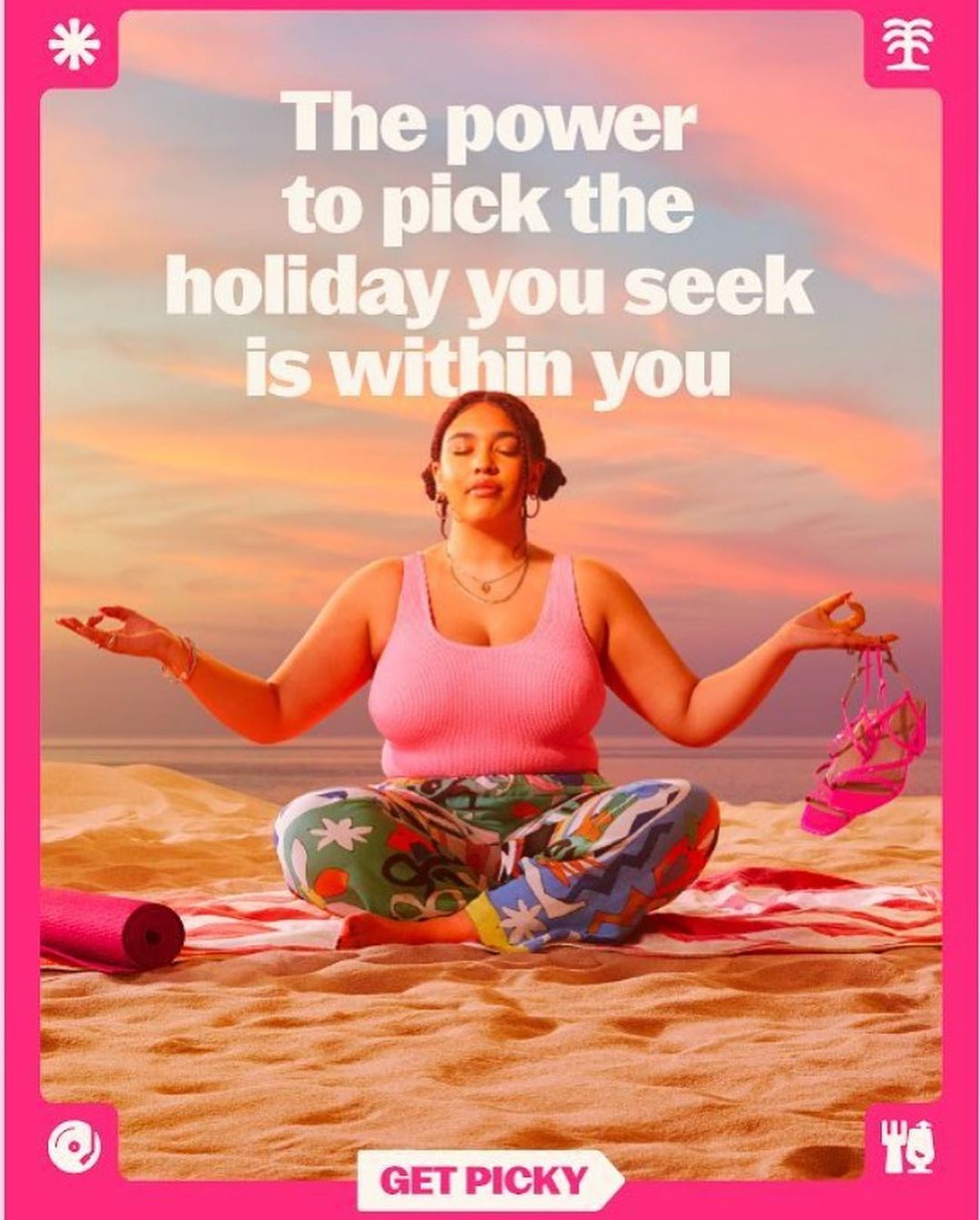 Woman meditating on a beach at sunset, wearing colorful pants and a pink tank top. Yoga mat and sandals are nearby. The sky is pink.