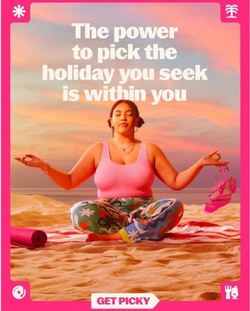 Woman meditating on a beach at sunset, wearing colorful pants and a pink tank top. Yoga mat and sandals are nearby. The sky is pink.