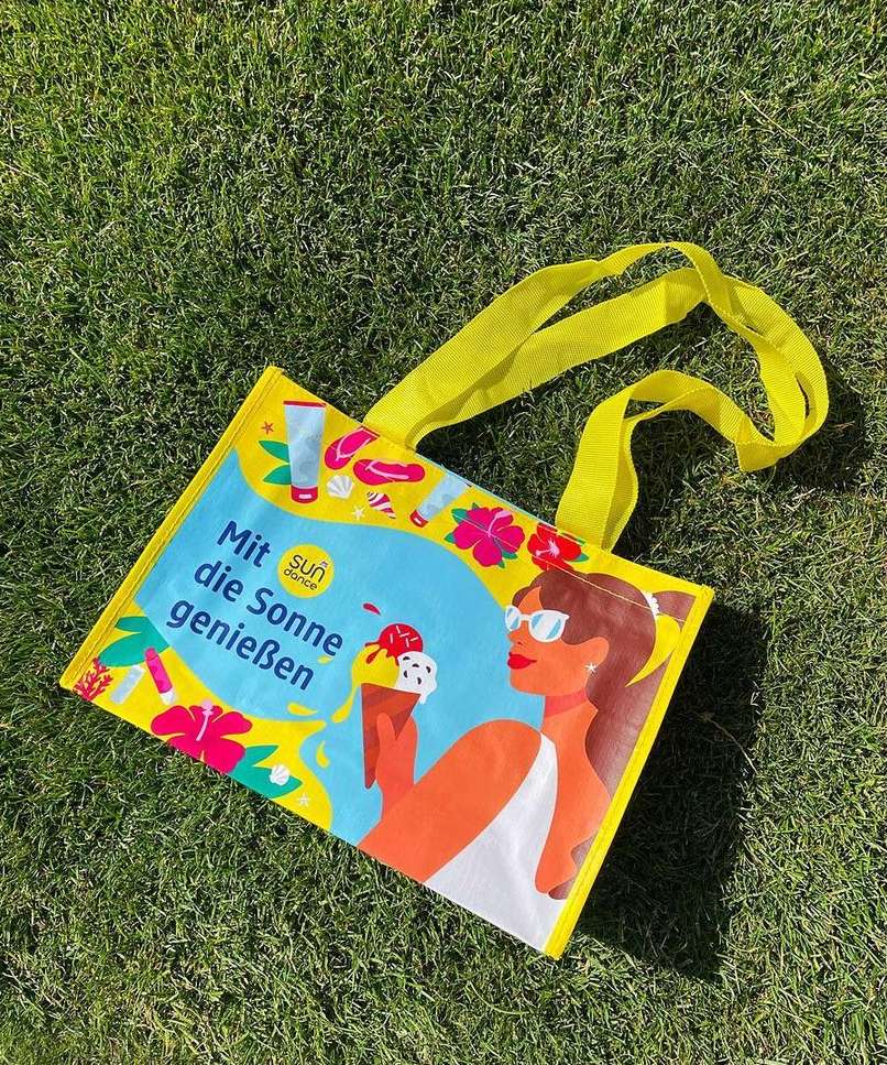 Graphic tote bag featuring an illustration of a woman holding an ice cream cone, sunglasses, and text on green grass.
