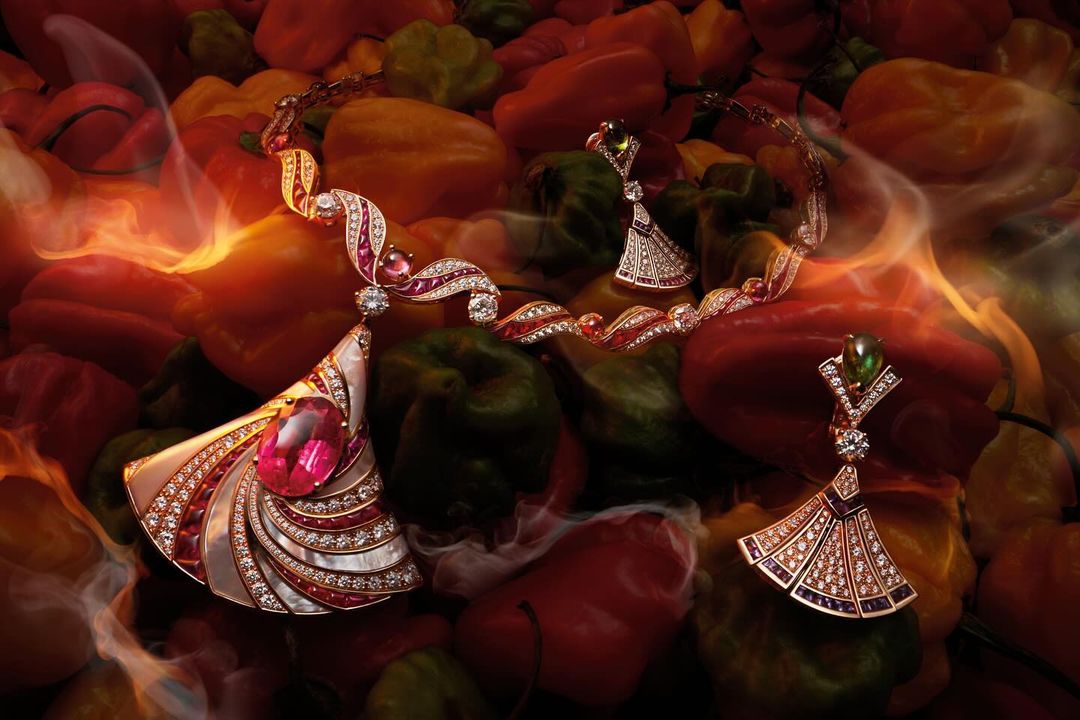 High-angle product shot of diamond and gemstone jewellery including earrings and necklace set on vibrant background of peppers, food styling.