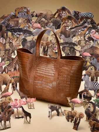 Brown crocodile tote bag surrounded by paper cutouts of wild animals including elephants, lions, tigers, zebras, flamingos, and giraffes.