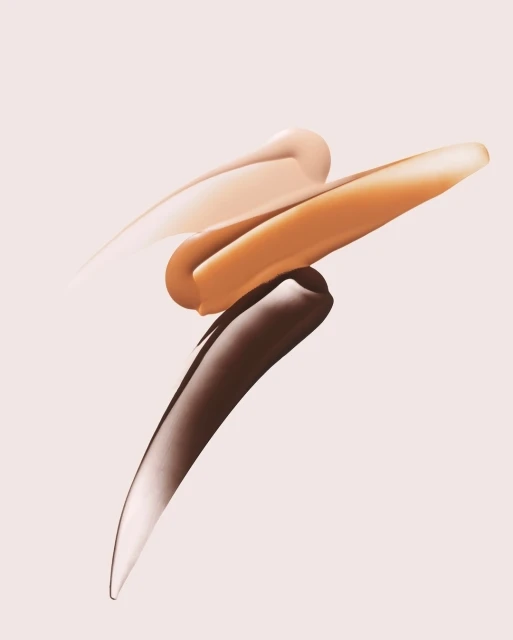 Cosmetic foundation swatches in light, medium, and dark tones displayed against a light pink background in a studio setting.