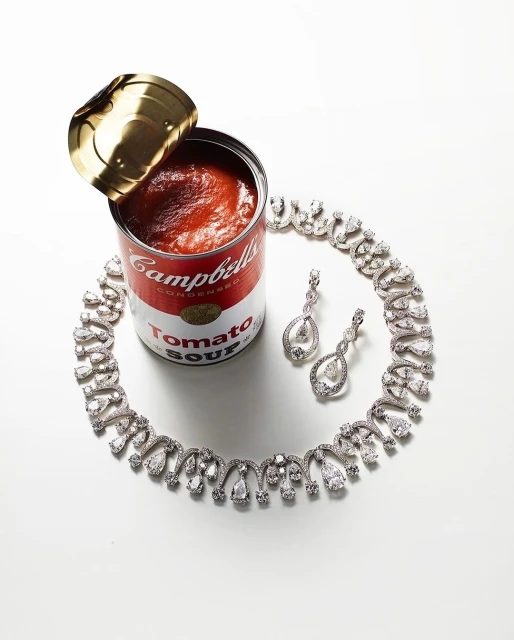 Silver diamond necklace and earrings displayed with a can of Campbell's Tomato Soup on a white background, studio lighting.