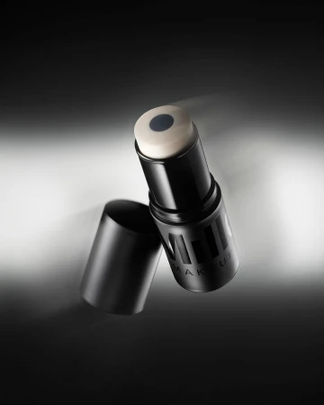 Close-up of a black Milk Makeup product stick and cap against a gradient gray background, showcasing beauty product for cosmetic use.