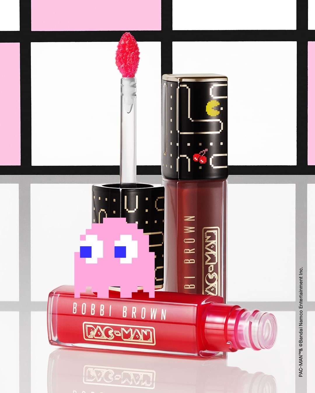 Bobbi Brown Pac-Man lip gloss in red and black packaging, featuring a pink Pac-Man ghost, against a patterned background.