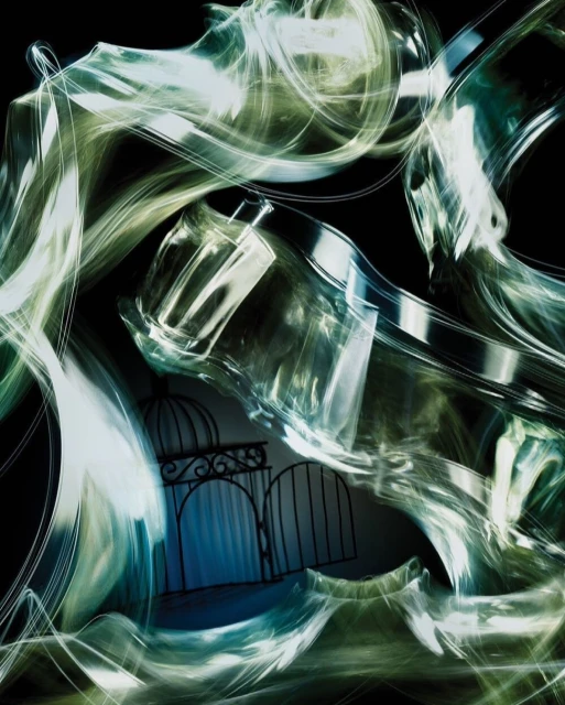 Abstract still life with perfume bottle and wrought-iron gate set against a dark background with swirling, blurred lighting effects.