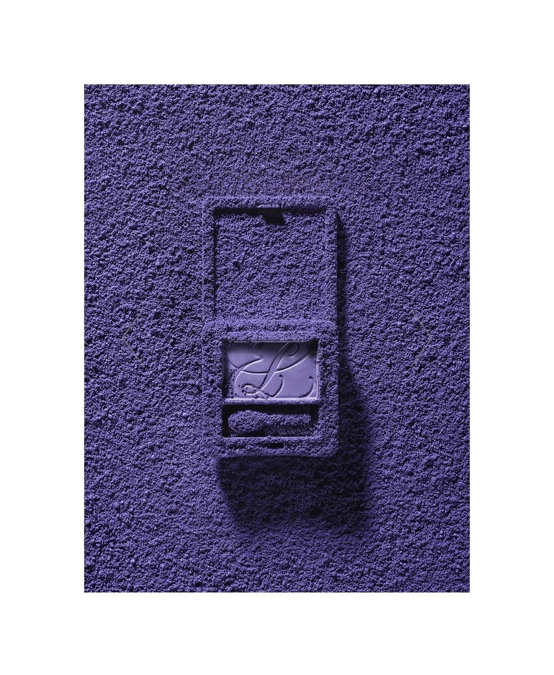 Eye shadow powder covers a purple makeup compact on a white surface, creating a monochromatic beauty still life.