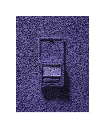 Eye shadow powder covers a purple makeup compact on a white surface, creating a monochromatic beauty still life.
