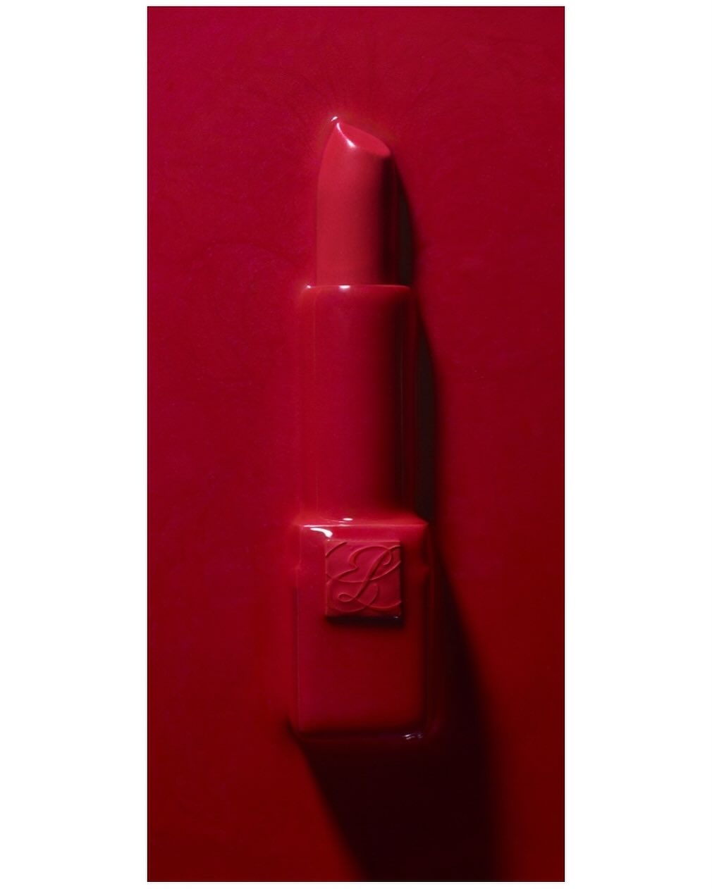 Close-up of red lipstick on a red background, showcasing a smooth texture and vibrant color for beauty and cosmetic marketing.