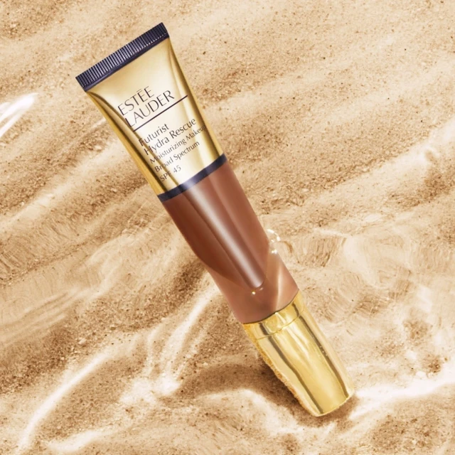 Estee Lauder Futurist Hydra Rescue Moisturizing Makeup on sand with water. Beauty shot for cosmetics, makeup, skincare, and summer.