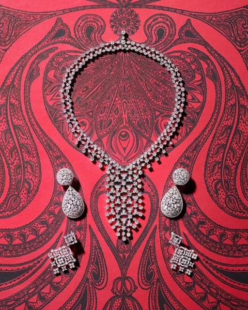Elegant diamond necklace with drop earrings and stud earrings showcased on a red patterned surface, emphasizing luxury and detail.