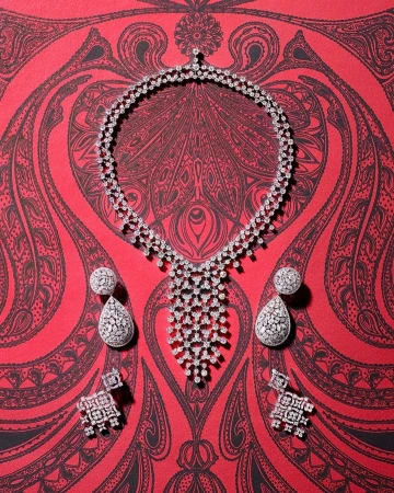 Elegant diamond necklace with drop earrings and stud earrings showcased on a red patterned surface, emphasizing luxury and detail.