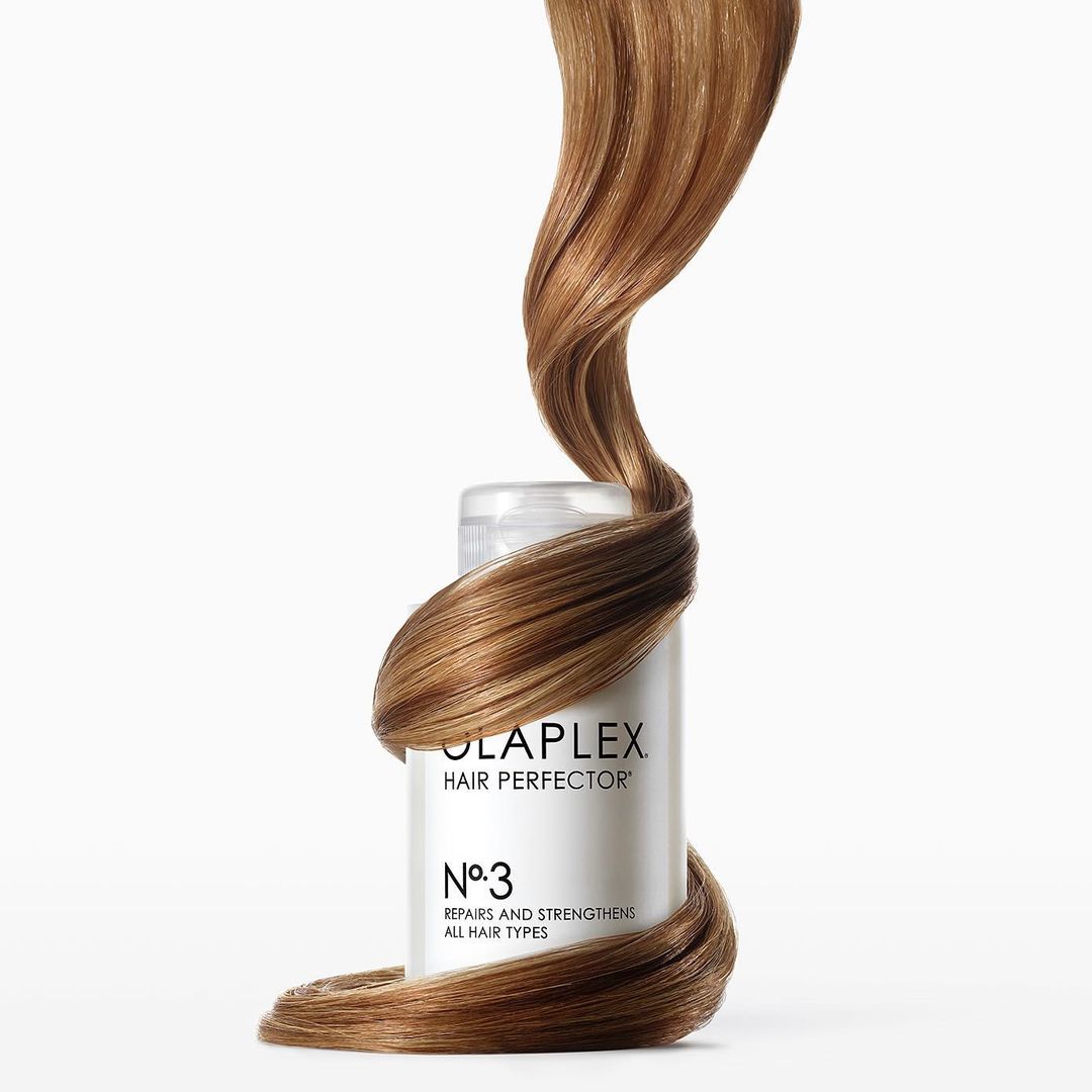 Olaplex Hair Perfector No. 3 bottle with hair wrapped around it against a white background, showcasing beauty and haircare.