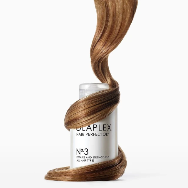 Olaplex Hair Perfector No. 3 bottle with hair wrapped around it against a white background, showcasing beauty and haircare.