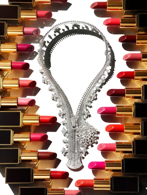 Overhead shot of lipstick tubes in various shades surrounding a diamond zipper necklace on a white background. Beauty and fashion concept.