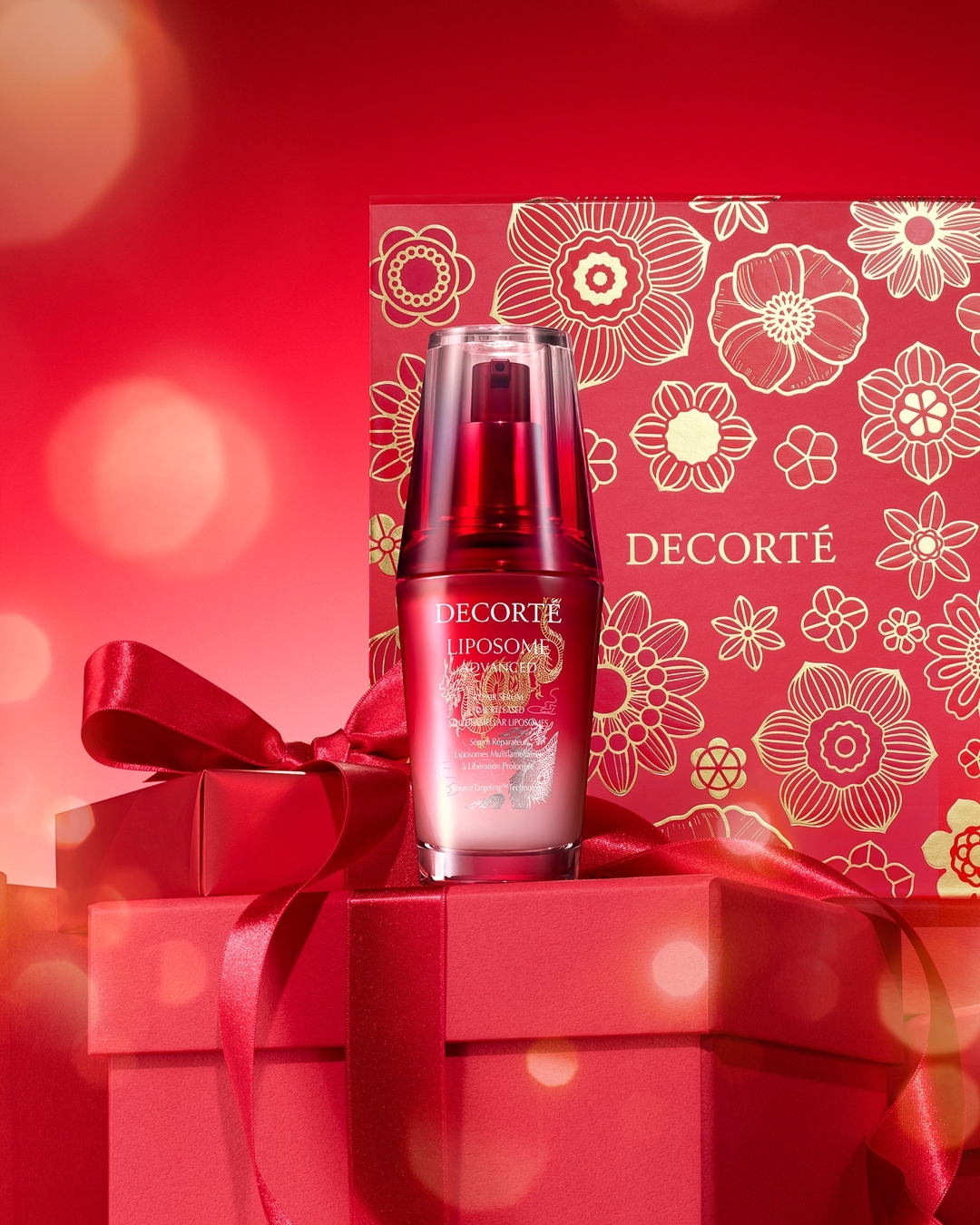 Decorté Liposome serum bottle atop stacked red gift boxes with floral patterned background, product shot for beauty and skincare promotion.