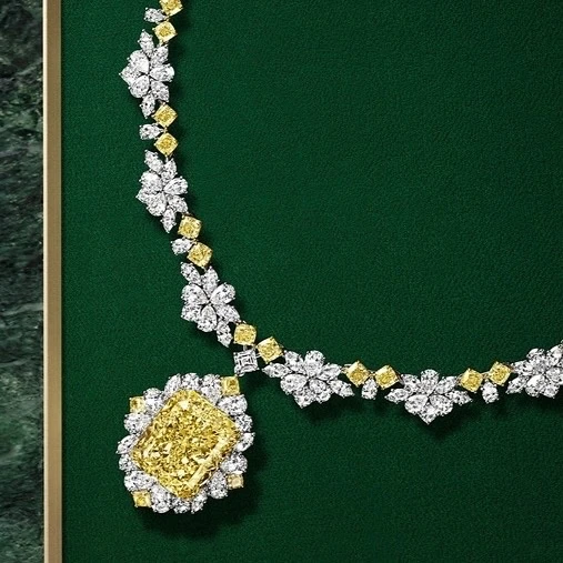 Radiant-cut yellow diamond necklace with white diamond floral details on a dark green background, offering a luxurious and elegant aesthetic.