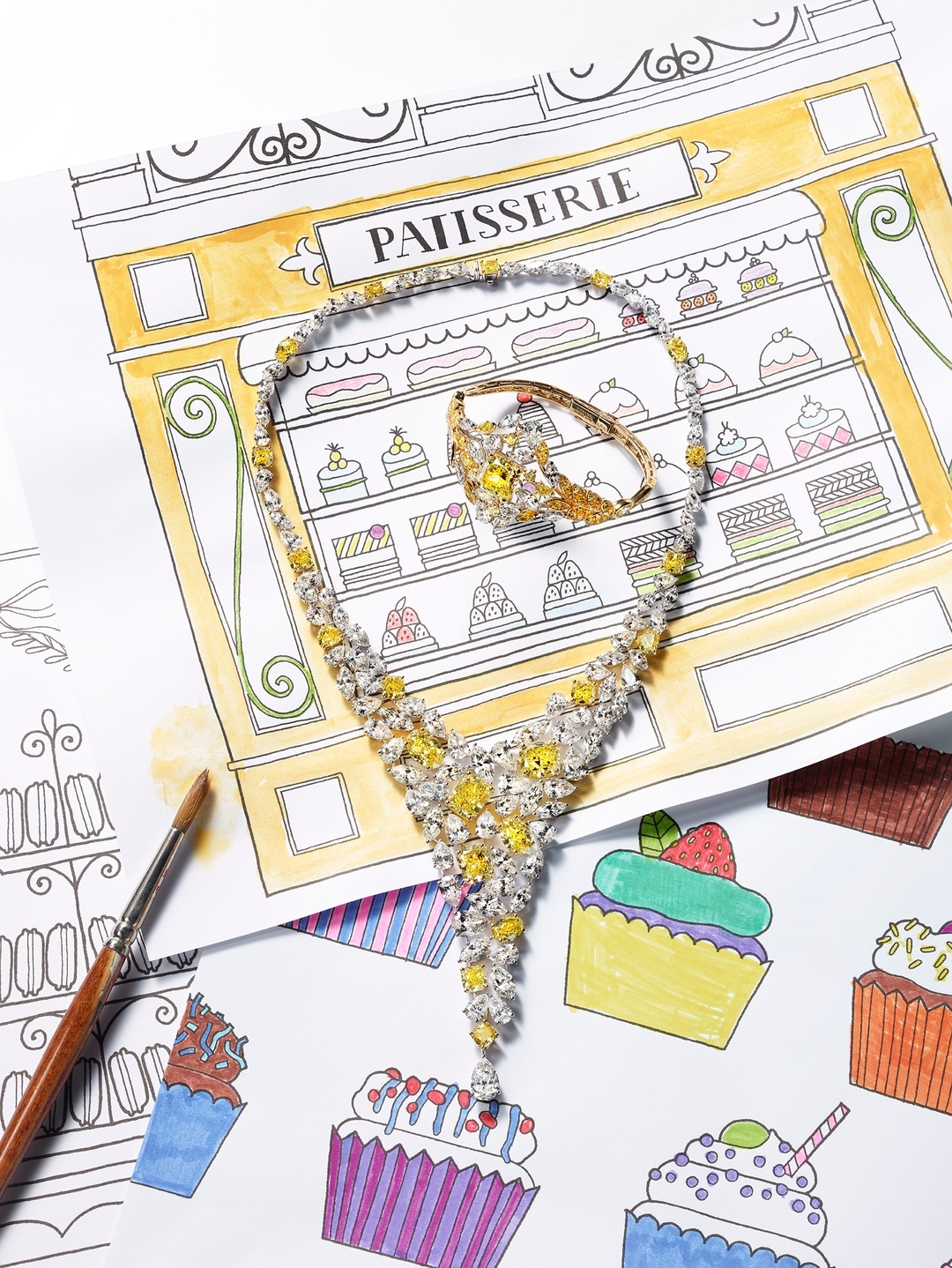 Elegant yellow diamond necklace and ring displayed on an illustrated background of a patisserie and cupcakes. Jewelry product shot.
