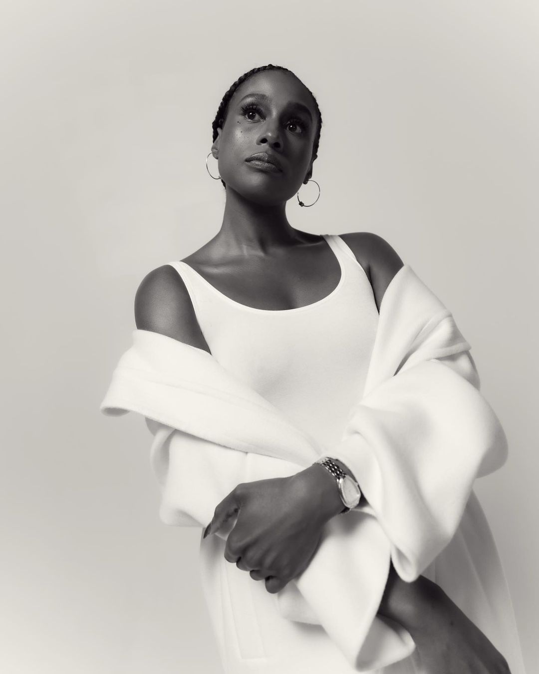 Monochrome portrait of an adult female wearing white top and white jacket looking up in an indoor photo studio setting.