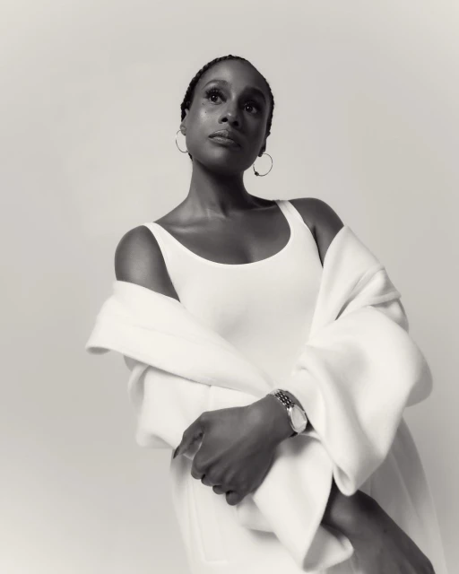 Monochrome portrait of an adult female wearing white top and white jacket looking up in an indoor photo studio setting.