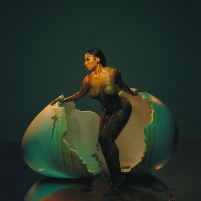 Striking studio shot of an adult woman partially emerging from a cracked egg, with a glossy reflective surface and dark, moody lighting.