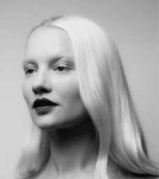 Monochrome portrait of a woman with long light hair and dark lipstick against a neutral background