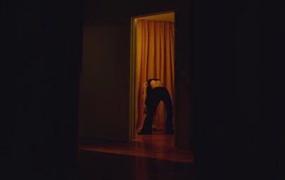 Dancer bending backward in a warmly lit doorway by Kanya Iwana
